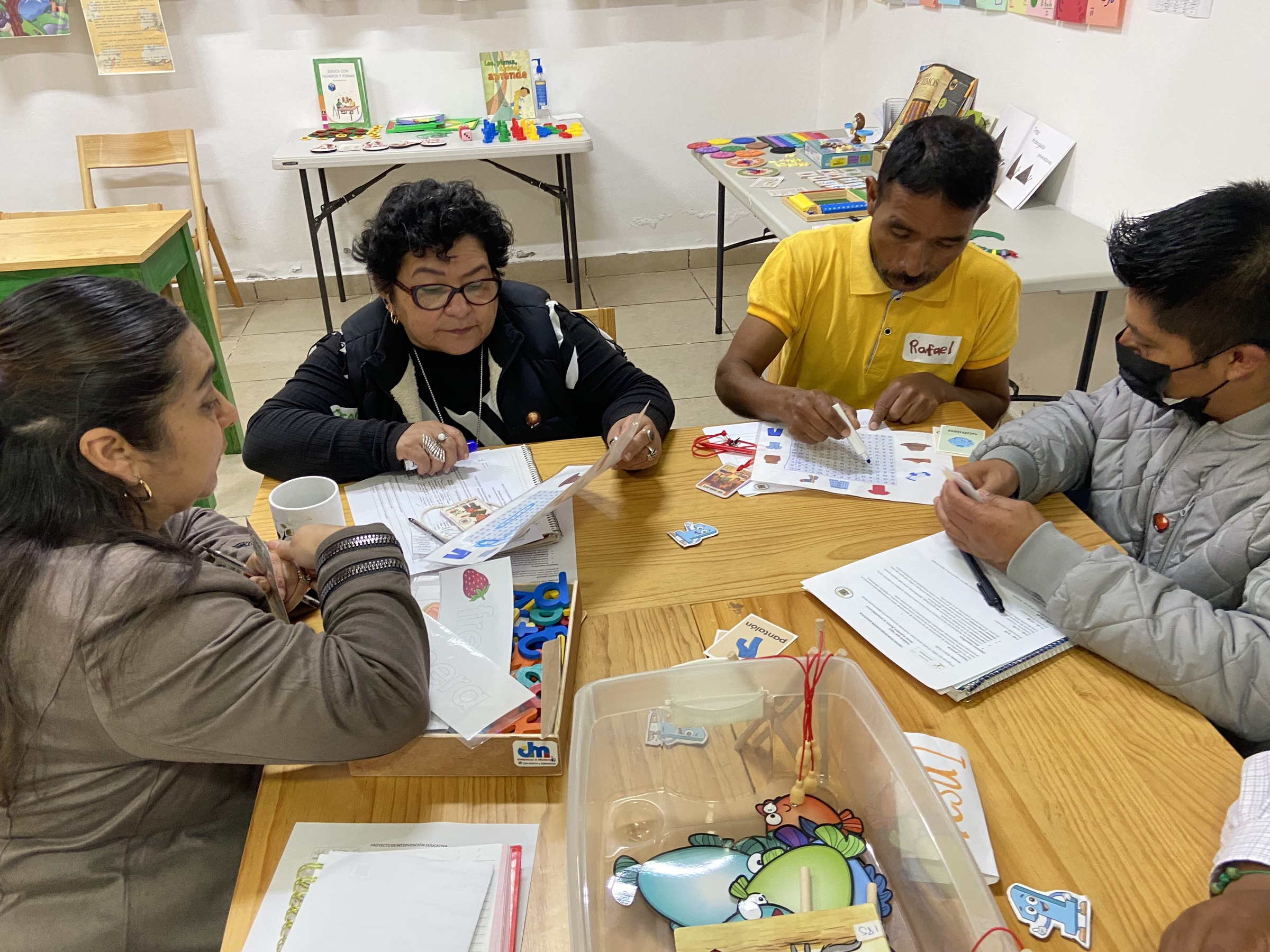 Personas trabajan con materiales impresos alrededor de una mesa.