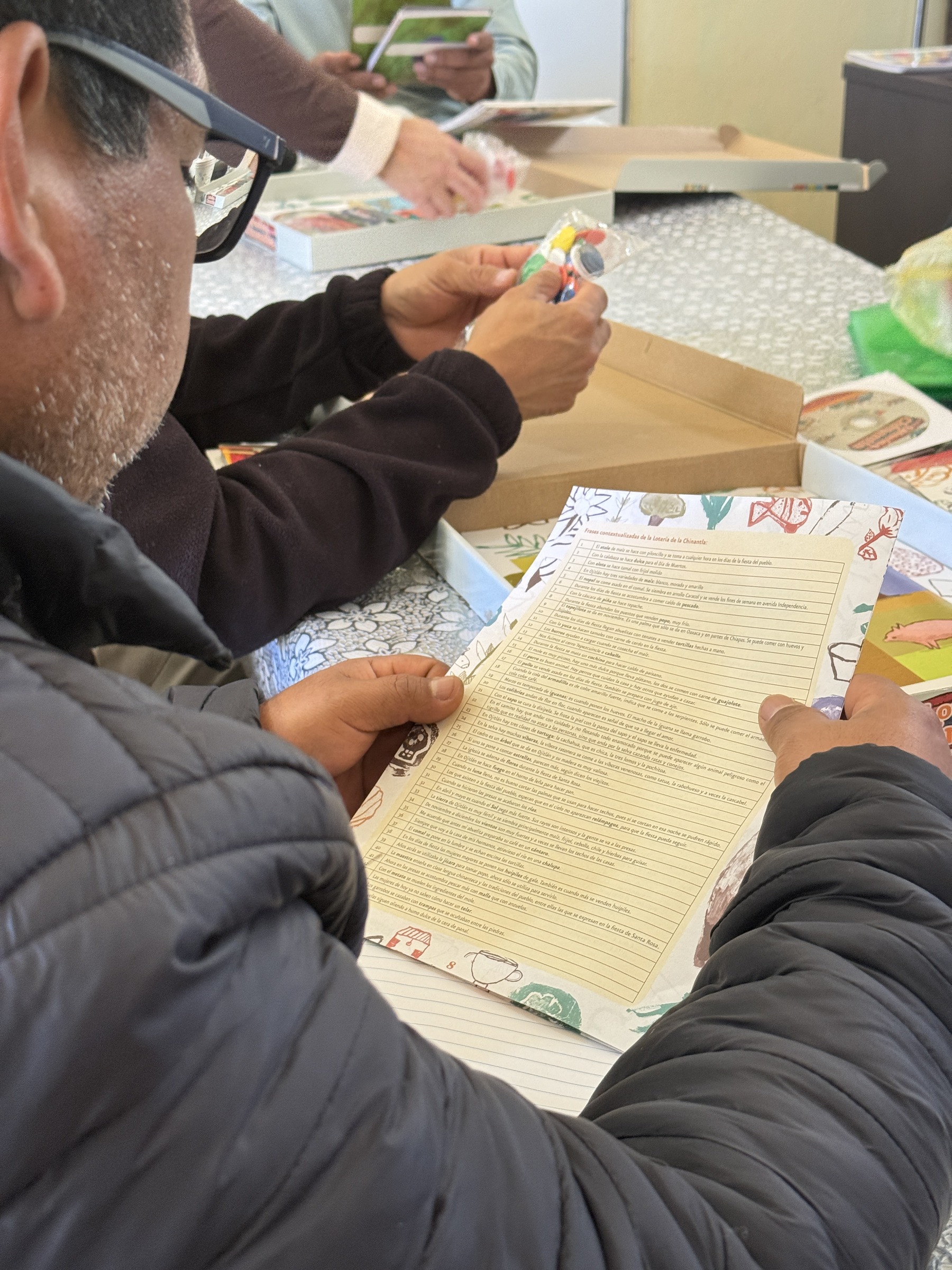 Personas leen y escriben sobre materiales impresos alrededor de una mesa.